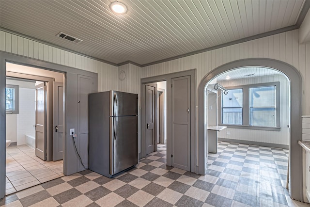 kitchen with freestanding refrigerator, a healthy amount of sunlight, visible vents, and arched walkways