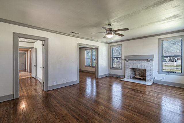 unfurnished living room featuring dark wood-type flooring, visible vents, a ceiling fan, a brick fireplace, and crown molding