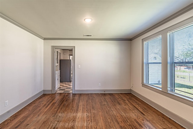 unfurnished room with dark wood-type flooring, visible vents, crown molding, and baseboards