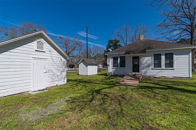 exterior space featuring an outbuilding, a yard, a chimney, and a storage unit