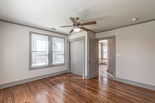 unfurnished bedroom featuring dark wood-type flooring, a closet, visible vents, and baseboards