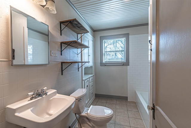 full bath featuring tile patterned flooring, a bathing tub, toilet, a sink, and tile walls