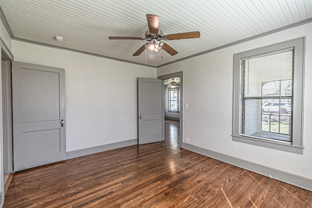 empty room featuring dark wood-style flooring, crown molding, a ceiling fan, wood ceiling, and baseboards