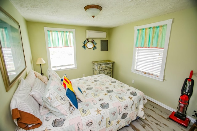 bedroom featuring a textured ceiling, multiple windows, a wall mounted AC, and wood finished floors