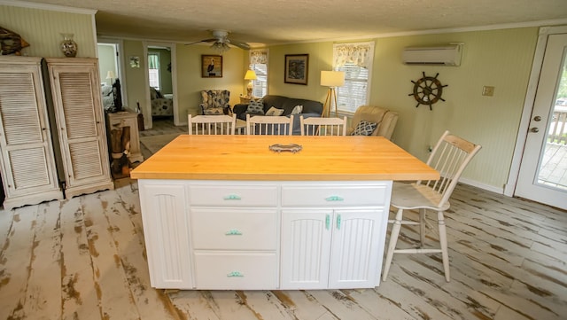 kitchen featuring a textured ceiling, a ceiling fan, white cabinets, and an AC wall unit