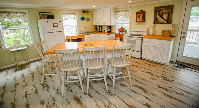 kitchen featuring butcher block countertops, white appliances, and white cabinetry