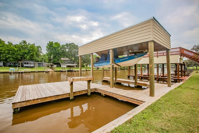 view of dock featuring a water view, a lawn, and boat lift