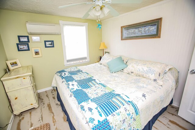 bedroom featuring a textured ceiling, ceiling fan, a wall mounted AC, and baseboards