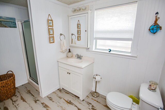 bathroom featuring baseboards, a shower stall, toilet, and vanity