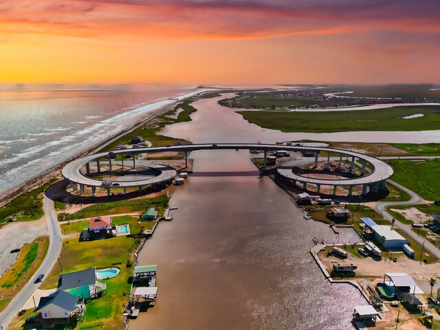 aerial view at dusk featuring a view of the beach and a water view