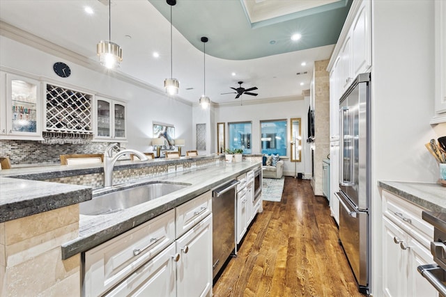 kitchen featuring light stone counters, crown molding, appliances with stainless steel finishes, white cabinetry, and a sink