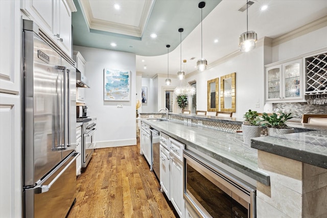 kitchen with high end appliances, a raised ceiling, visible vents, and crown molding