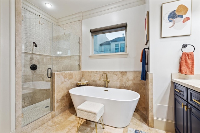 full bathroom with tile walls, ornamental molding, a stall shower, vanity, and a freestanding tub