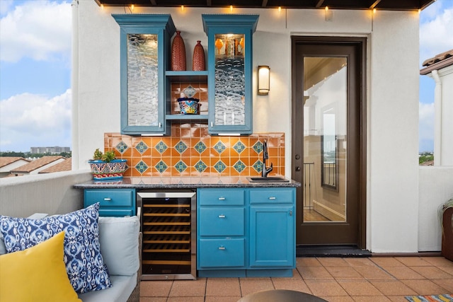 bar featuring wine cooler, light tile patterned floors, tasteful backsplash, a sink, and bar area