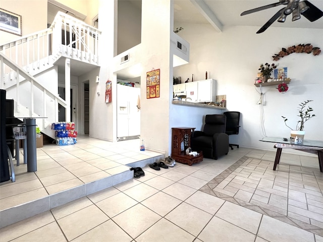 tiled living room with visible vents, ceiling fan, a high ceiling, stairs, and beam ceiling