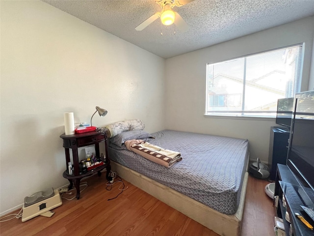 bedroom with a ceiling fan, a textured ceiling, and wood finished floors