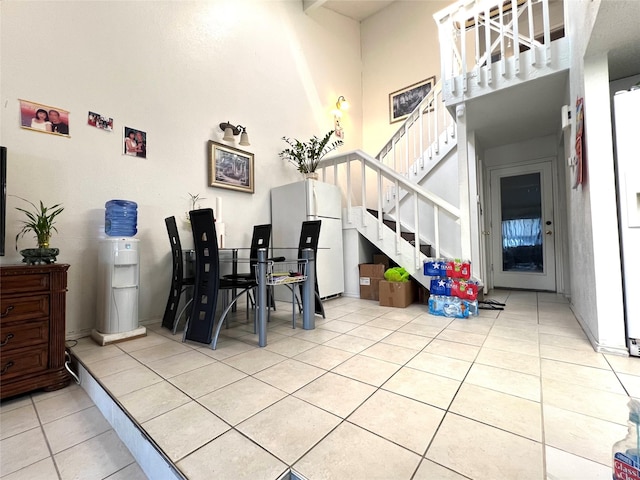 dining space featuring light tile patterned floors, stairway, and a towering ceiling