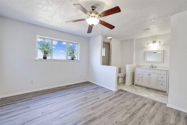 bathroom featuring a textured ceiling, toilet, wood finished floors, vanity, and baseboards