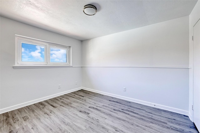 spare room with a textured ceiling, baseboards, and wood finished floors