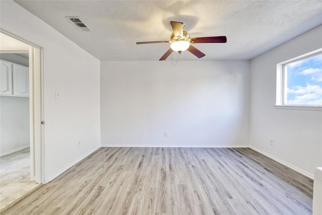 unfurnished room with visible vents, ceiling fan, a textured ceiling, and wood finished floors