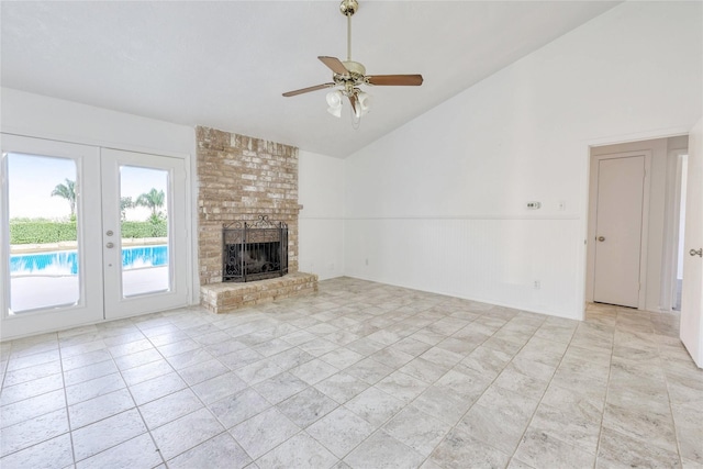 unfurnished living room with high vaulted ceiling, a fireplace, a ceiling fan, french doors, and wainscoting