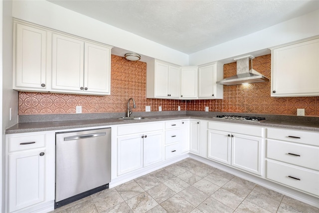 kitchen featuring stainless steel appliances, a sink, decorative backsplash, and wall chimney exhaust hood