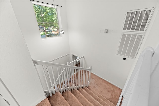 stairway with carpet floors, a heating unit, visible vents, and baseboards