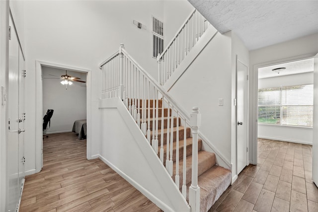 stairs featuring a textured ceiling, baseboards, and wood finished floors