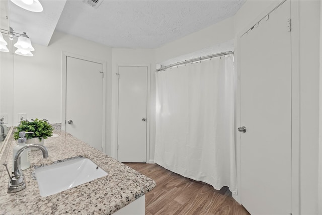 bathroom with a textured ceiling, wood finished floors, and a sink