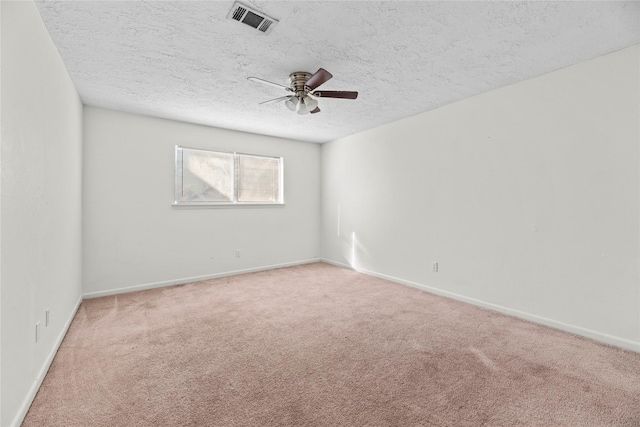 empty room with light carpet, a textured ceiling, visible vents, and baseboards