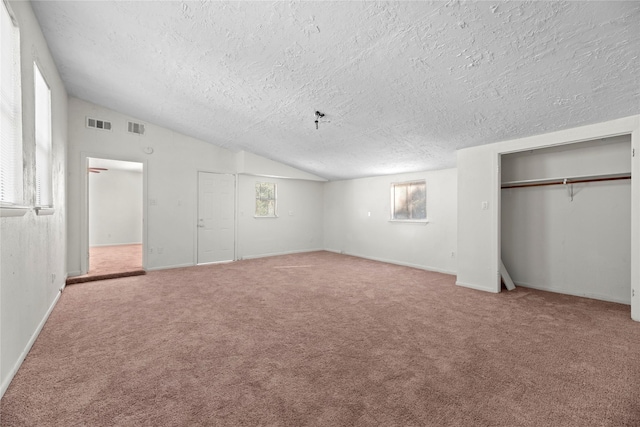 unfurnished bedroom with carpet, visible vents, vaulted ceiling, and a closet