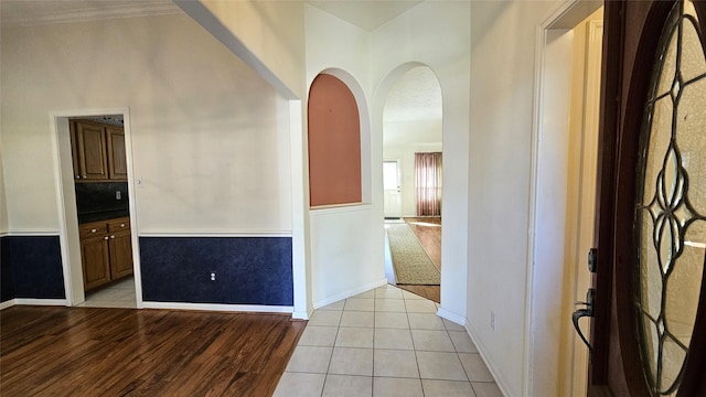 unfurnished room with arched walkways, light wood-style flooring, and baseboards