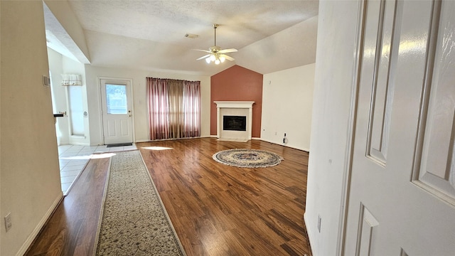 unfurnished living room with baseboards, a ceiling fan, lofted ceiling, wood finished floors, and a fireplace