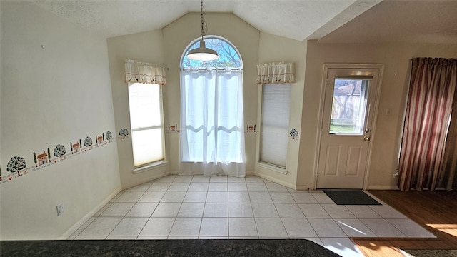 foyer entrance featuring light tile patterned floors, plenty of natural light, vaulted ceiling, and a textured ceiling