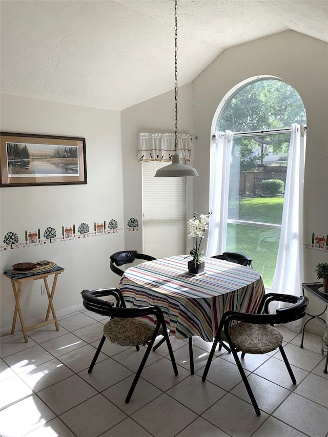 dining area with lofted ceiling, baseboards, a textured ceiling, and light tile patterned flooring