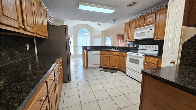 kitchen featuring brown cabinets, visible vents, a sink, white appliances, and a peninsula