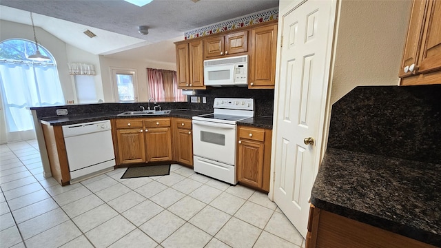 kitchen with a peninsula, white appliances, brown cabinets, and a sink