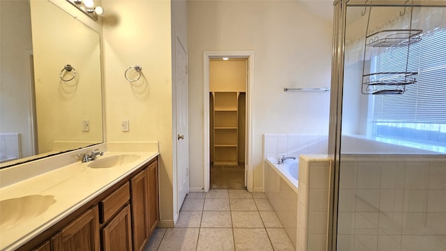 full bathroom with double vanity, baseboards, a sink, tile patterned flooring, and a bath