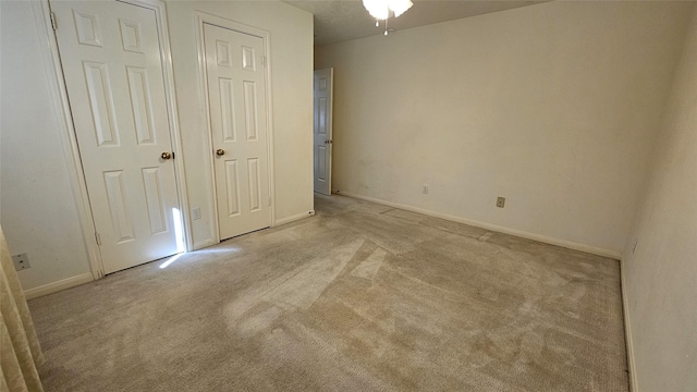 unfurnished bedroom featuring light carpet and baseboards