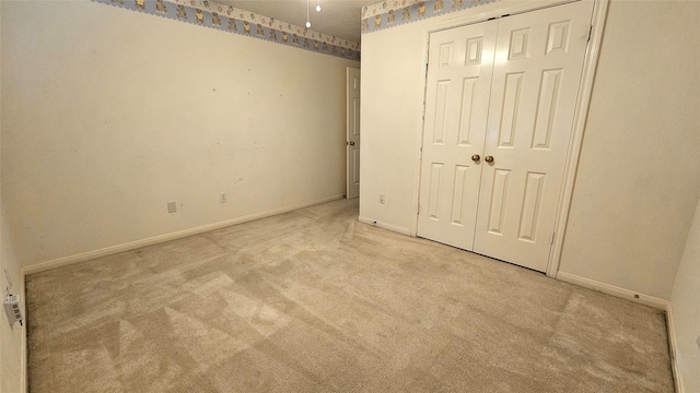 unfurnished bedroom featuring a closet, baseboards, and carpet flooring