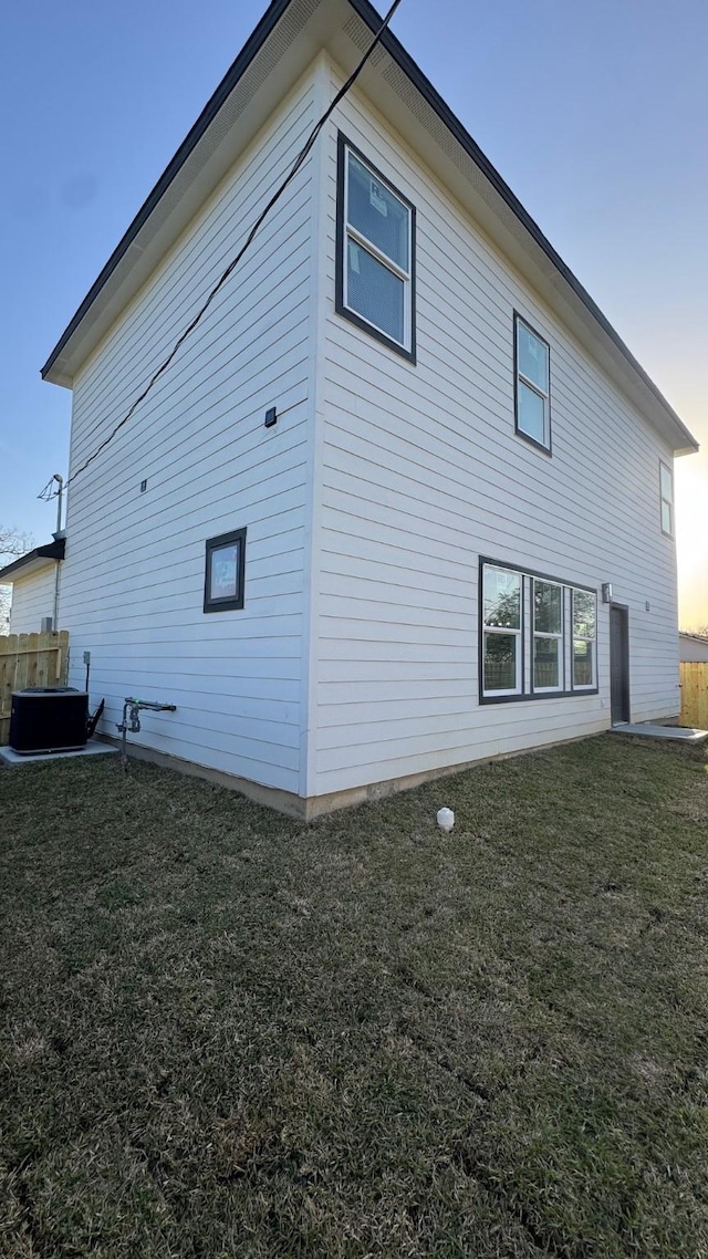 view of property exterior with central AC and a lawn