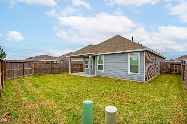 rear view of property with a lawn, a patio, a shingled roof, and a fenced backyard