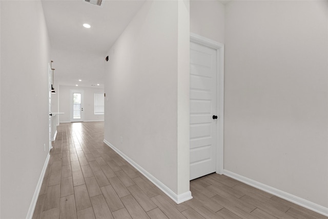 hall featuring wood finish floors, visible vents, baseboards, and recessed lighting