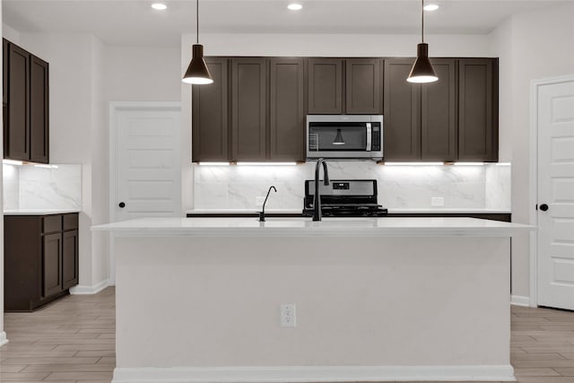 kitchen featuring dark brown cabinetry, light wood-style flooring, appliances with stainless steel finishes, and light countertops