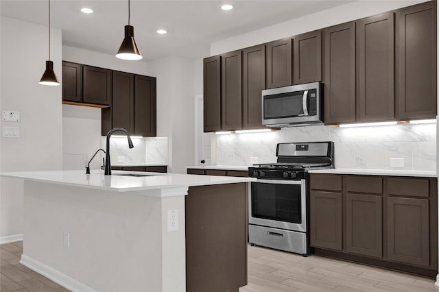 kitchen featuring a sink, decorative light fixtures, appliances with stainless steel finishes, light countertops, and decorative backsplash