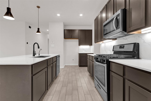 kitchen featuring a sink, light countertops, dark brown cabinets, appliances with stainless steel finishes, and backsplash