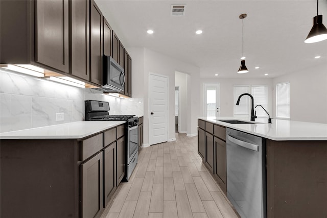 kitchen with visible vents, a sink, tasteful backsplash, stainless steel appliances, and dark brown cabinetry