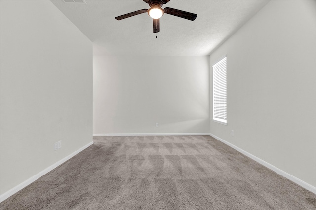 carpeted spare room featuring visible vents, a ceiling fan, and baseboards