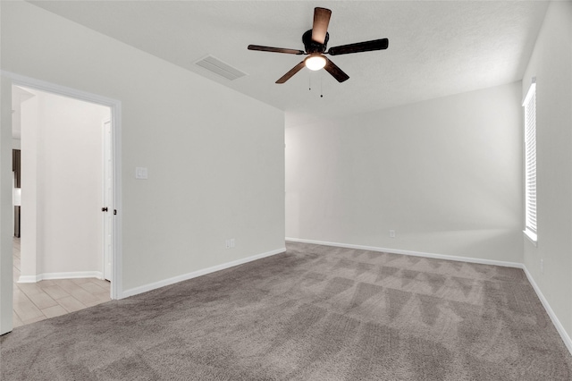 carpeted spare room featuring visible vents, baseboards, and ceiling fan