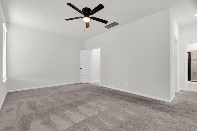 carpeted spare room with visible vents, ceiling fan, and baseboards